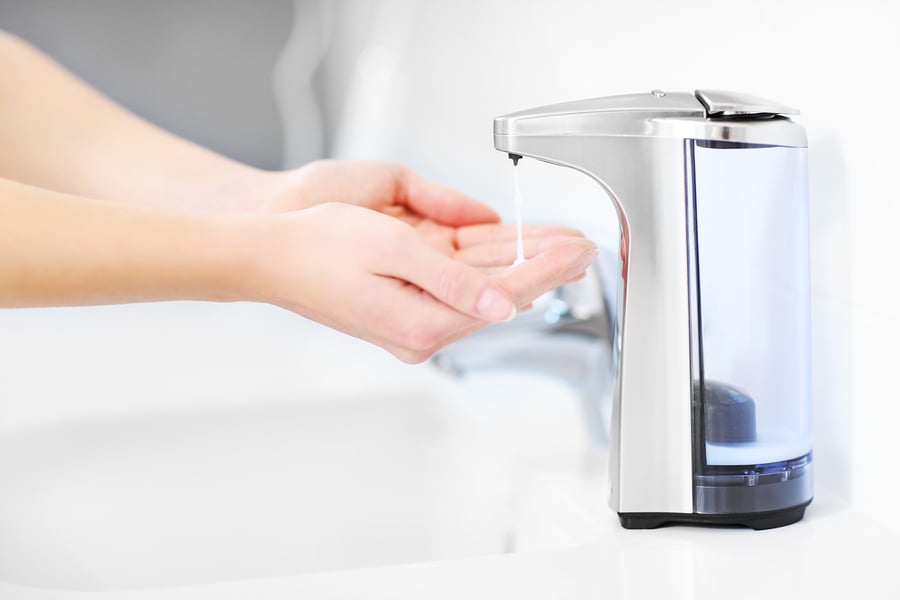 Close up of female hands using automatic soap dispenser