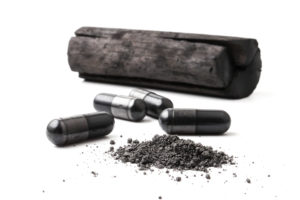 Charcoal (activated carbon) in capsules on white background