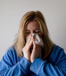 woman sneezing with a winter cold bug